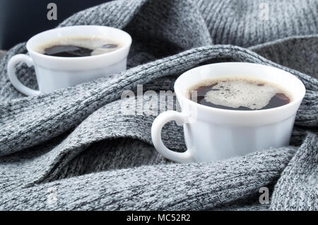 Zwei weiße Tassen Kaffee verpackt in Falten der grauen Schal mit einer kleinen Schärfentiefe Stockfoto