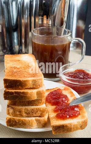 Gebratene Toast mit Erdbeermarmelade auf dem Tisch mit Küchenutensilien Stockfoto
