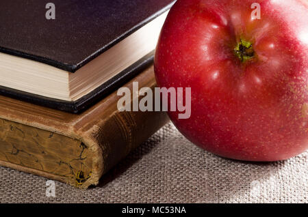 Detail der alten Bücher in Hardcover und close-up red apple auf alten grau Tischdecke Stockfoto