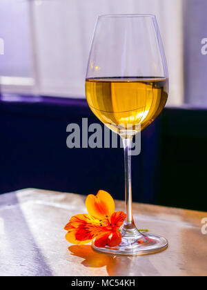 Glas weiss Wein mit Blume auf Vintage shabby Holz- Tisch im Restaurant. Stockfoto