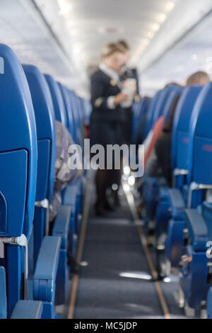 Die Defokussierten Stewardess serviert Erfrischungen an Bord des Flugzeugs. Ein Blick auf den Korridor des Flugzeuges. Stockfoto