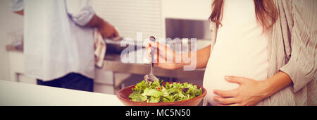 Schwangere Frau mischen einen Salat in der Küche Stockfoto