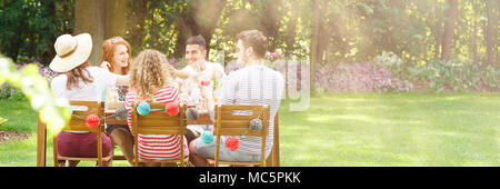 Panorama der glückliche Freunde beim Mittagessen im Garten während einer Geburtstagsfeier Stockfoto