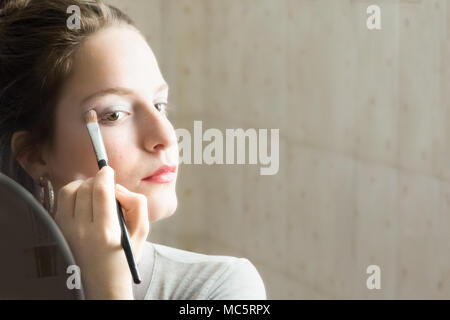 Jugendlicher Mädchen Anwendung Lidschatten ihr Spiegelbild auf einem Spiegel zu Hause suchen. Stockfoto