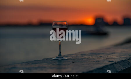 Glas Rotwein mit orangen Hintergrund bei Sonnenuntergang Stockfoto