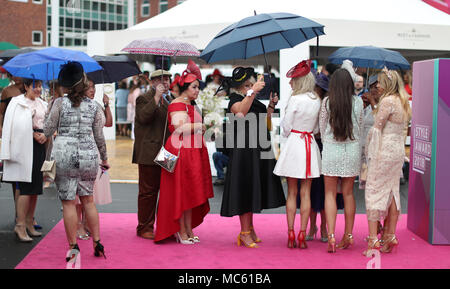 Racegoers Unterschlupf vor dem Regen während der Damen Tag des 2018 Randox Gesundheit Grand National in Aintree Racecourse, Liverpool. Stockfoto