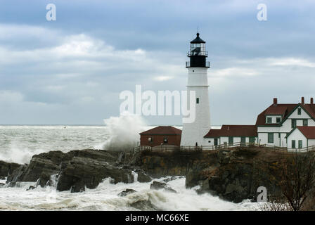 Riesige Wellen gegen Portland Head Lighthouse wie Sonnenlicht bricht durch Gewitterwolken. Es ist der älteste Leuchtturm in Maine und die zweitälteste Stockfoto