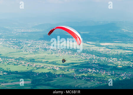 Gleitschirm über Dorf in den Bergen im Sommer Tag fliegen. Stockfoto