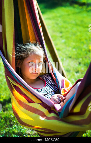 Kind, Mädchen, das sich in einem sonnigen Hängematte auf Urlaub. Stockfoto