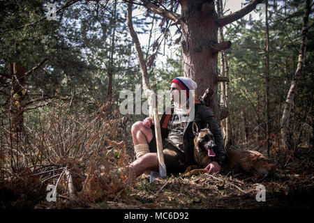 Stock Foto eines Mannes im Wald sitzt mit seinem Hund Stockfoto