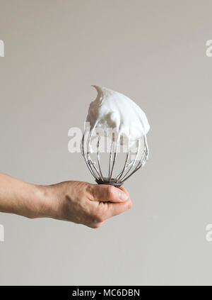 Woman's Hand mit einem Mixer verrühren Mit geschlagener Eischnee Stockfoto