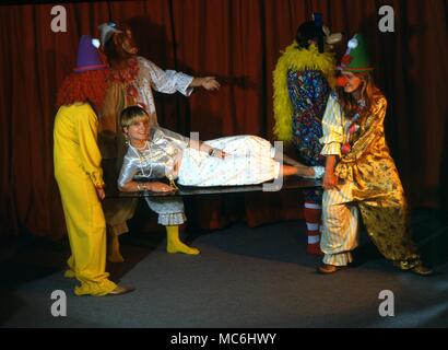 Stufe Magic-verschwinden Mädchen. Ein Mädchen ist auf einer Glasplatte, die von einer Gruppe von Clowns durchgeführt. Stockfoto