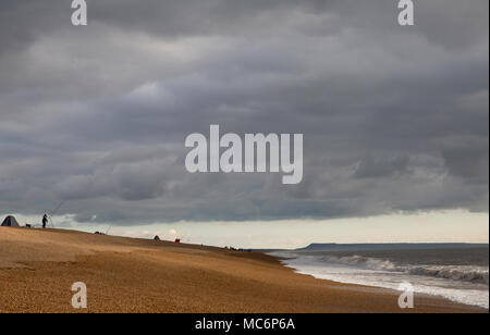 Strand angler angeln am Chesil Beach, nach einem Sturm im Januar 2018. Angeln nach einem Sturm eine produktive Zeit sein kann, für einen Fisch, um zu versuchen Stockfoto