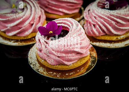 Handgefertigte rosa Zephyr Cookie mit violetten Blumen auf Schwarz Spiegel Hintergrund Stockfoto
