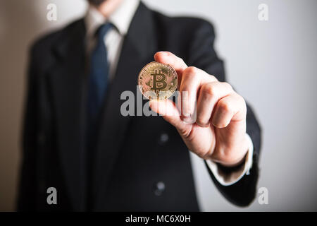 Golden Bitcoin in einer Hand und Digitall Symbol einer neuen virtuelle Währung. Mann bekommen Geld von bitcoin Geschäft. Stockfoto