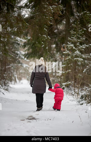 Junge schöne Mädchen mit Hut wihite posiert vor einem Winter Park Hintergrund und spielen mit den süßen Mädchen mit dem Schnee im Wald Stockfoto