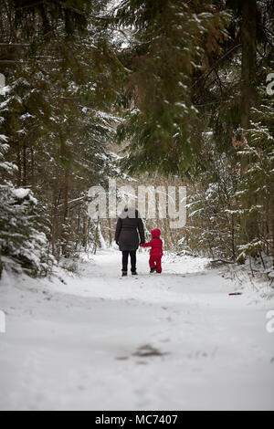 Junge schöne Mädchen mit Hut wihite posiert vor einem Winter Park Hintergrund und spielen mit den süßen Mädchen mit dem Schnee im Wald Stockfoto