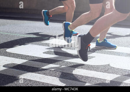 Detailansicht des synchronisierten Marathonläufer Füße und Beine mit Motion Blur im Licht des Morgens auf Stadt Asphaltstraße Stockfoto