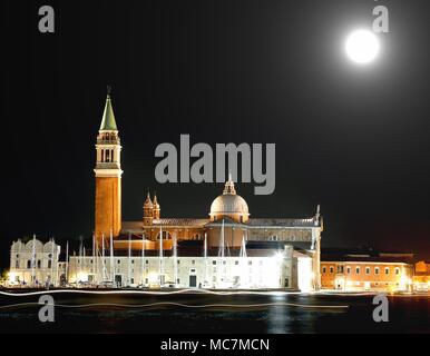 Beleuchtete Kirche von Saint Haupttouristenattraktionen in der venezianischen Lagune in Venedig bei Nacht und die hellen Spuren durch die vorbeifahrenden Schiffe Links witn Vollmond Stockfoto