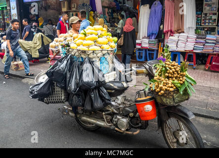 Eine Frau verkaufen Körbe voll von Mangos und mispeln von ihrem Motorrad auf einer Straße in Ho Chi Minh City, Vietnam. Stockfoto