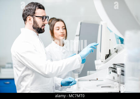 Laborassistenten in unifrom arbeiten mit professionellen medizinischen analizer im Labor Stockfoto