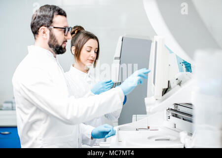 Laborassistenten in unifrom arbeiten mit professionellen medizinischen analizer im Labor Stockfoto