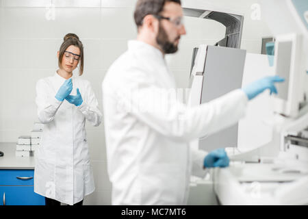 Laborassistenten in unifrom arbeiten mit professionellen medizinischen analizer im Labor Stockfoto