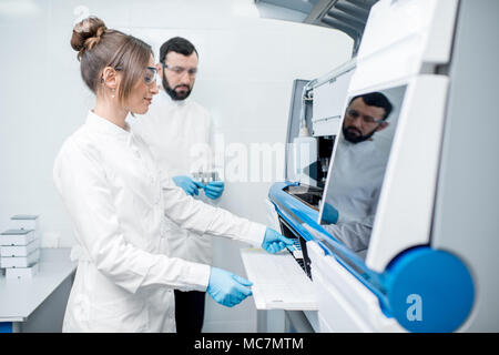 Laborassistenten in unifrom arbeiten mit professionellen medizinischen analizer im Labor Stockfoto