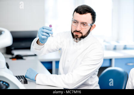 Männliche Laboratory Assistant Kontrolle Reagenzglas Im modernen Labor sitzen Stockfoto