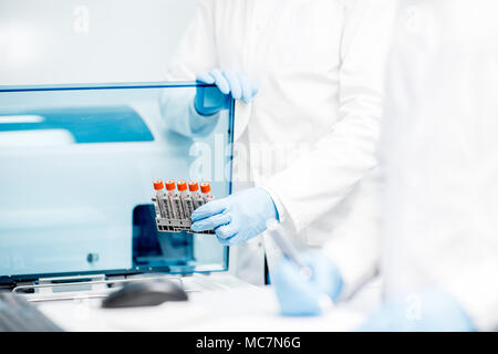 Laboratory Assistant Füllung Röhrchen in den Analysator Maschine Stockfoto