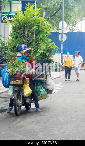 Eine Frau auf einem Motorrad mit Topfpflanzen in Ho Chi Minh City, Vietnam geladen. Stockfoto