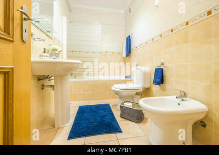 Klassik Bad in warmen Farben und mit blauer Bettwäsche und Decke Stockfoto