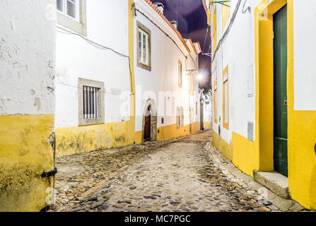 Schmale Straße mit weißen und gelben Häuser bei Nacht in Évora, Alentejo, Portugal Stockfoto