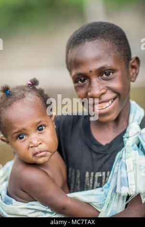 Porträt eines lächelnden Jungen des Insekts Menschen Stamm hält ein Kind, Swagup, oberen Sepik, Papua-Neuguinea Stockfoto