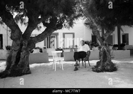 Mann mit einem Nickerchen im Schatten der zwei Bäume, Rhodos, Griechenland Stockfoto