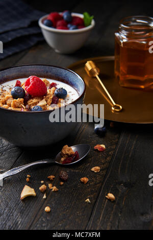 Frisches Müsli, Müsli mit Joghurt, Blaubeeren, Himbeeren, getrocknete Apfel und Preiselbeeren mit Chia Samen. Frischer gemischter Beerenfrucht und Ahornsirup. Stockfoto