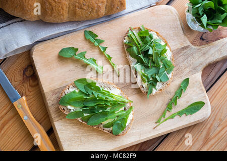 Zwei Scheiben Sauerteig Brot mit Butter und frischem Löwenzahn Blätter Stockfoto