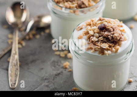 Joghurt mit Müsli aus Haferflocken, Rosinen, Puffreis, Schokolade und getrocknete Bananen. Gesundes Frühstück für die Familie. Gesunde Milchprodukte essen. Stockfoto