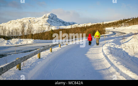 Mann und Kind entlang eine Schnee Straße in das Skigebiet von Beitostollen im Bezirk Oppland Norwegen bedeckt mit mount Bygdin in der Ferne Stockfoto