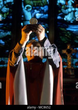 CHRISTIAN - Masse Priester der Anglikanischen Kirche, die Feier der Heiligen Messe. Er ist das Erhöhen der Host Stockfoto