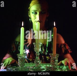 Mädchen üben Kerze Magic, mit drei Kerzen im Glas Inhaber Stockfoto