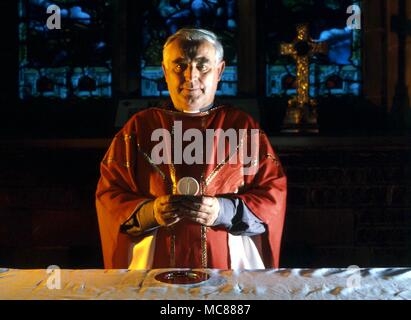 Christliche Priester der Anglikanischen Kirche feiert die Messe wird er in den Prozess der Erhöhung der Host Stockfoto