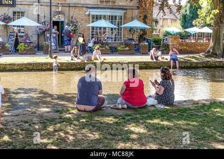 Das Dorf Bourton-on-the-Water ist für seinen malerischen High Street bekannt, die lange breite Grüns und den Fluss Windrush, läuft durch die FLANKIERT Stockfoto