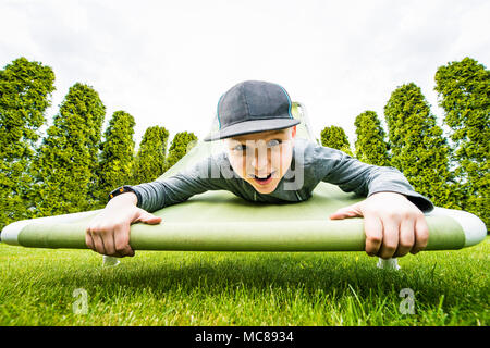 Junge hängen am angehobenen Hängesessel in den grünen Garten. Stockfoto