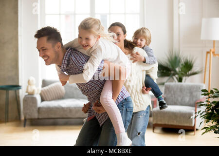 Glücklich liebende Vater huckepack kleine Tochter spielen, Mit der Familie zu Hause, Lächeln, Eltern, Kinder, die auf der Rückseite, Kinder, Junge und Mädchen Spaß tog Stockfoto