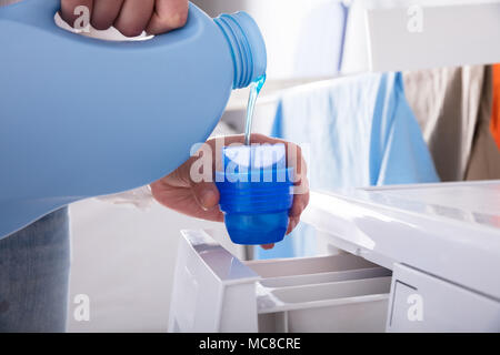 Nahaufnahme der Hand Gießen einer Person Waschmittel im Deckel Stockfoto