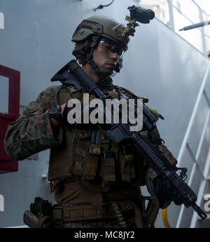 Ein Force Reconnaissance Marine mit maritimen Raid-Kraft, 31 Marine Expeditionary Unit, Beiträge Sicherheit bei der Durchführung von Besuchen, Board, Suche, und Beschlagnahme Training während der Amphibischen Integration Training an Bord der USNS Pililaau (T-AKR-304) Während im philippinischen Meer, 28. März 2018 im Gange. Marines mit Force Reconnaissance Platoon trainieren regelmäßig für schnelle, taktische Überfälle von Zielen sowohl auf Land und Meer. Die 31. MEU und amphibische Squadron 11 Verhalten AIT zur Vorbereitung auf die Zertifizierung der Übung und um sicherzustellen, dass die Bereitschaft zur Reaktion auf Krisen in der gesamten indopazifischen Region. Stockfoto