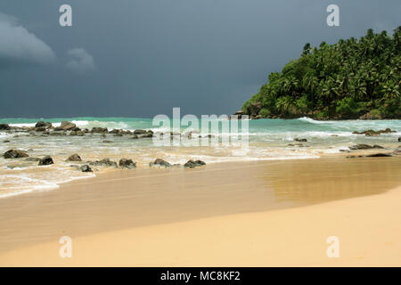 Strand in Mirissa, Sri Lanka: Türkis Wasser, feiner Sand, Wellen zum Surfen, mit schönen Felsen und gesäumt von Kokospalmen. Paradies! Stockfoto