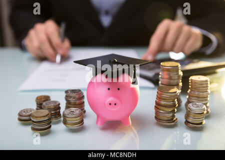 In der Nähe von Piggy Bank tragen Staffelung hat und gestapelte Münzen Vor Unternehmer Stockfoto