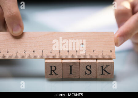 Nahaufnahme der Kaufmann Hand Risikomessung Blöcke mit hölzernen Lineal Stockfoto